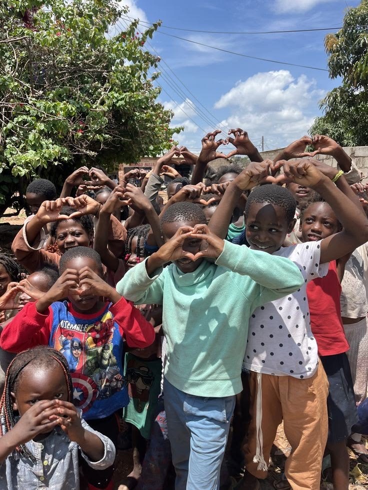 Community of young people forming heart shapes with their hands